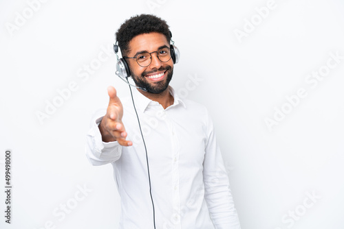 Telemarketer Brazilian man working with a headset isolated on white background shaking hands for closing a good deal