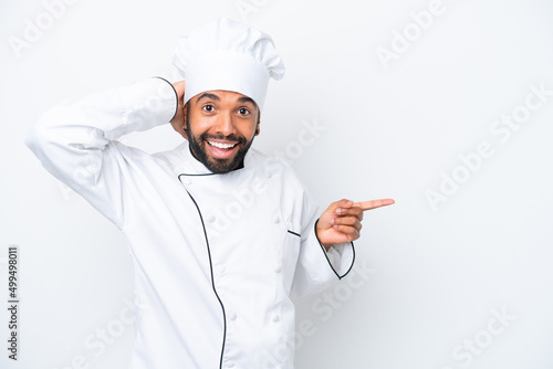 Young Brazilian chef man isolated on white background surprised and pointing finger to the side photo
