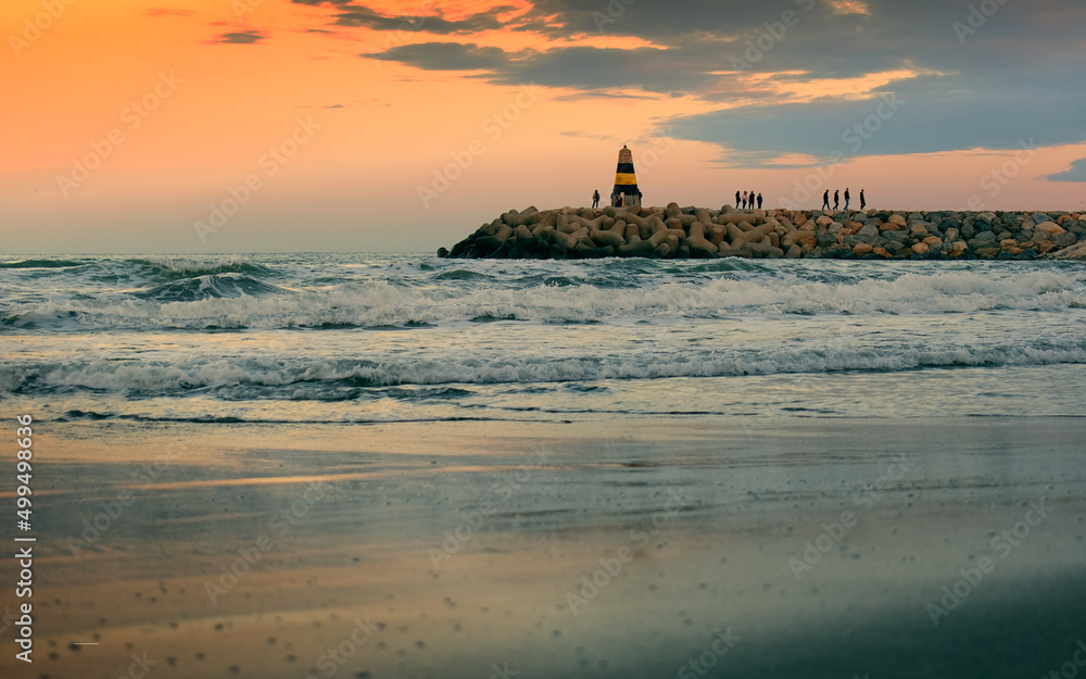 Beautiful sunset scenery of sandy beach and lighthouse at Banalmadena coast in Malaga, Spain 
