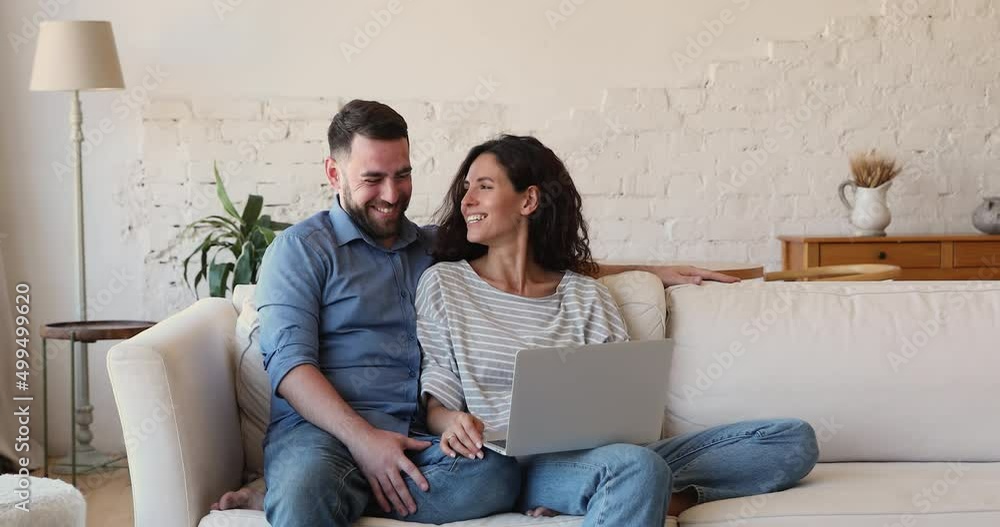 Happy millennial couple in love relax on sofa hold pc laugh on funny video on channel discuss web purchases surf social media. Loving young husband wife enjoy cozy evening at home chat using laptop Happy millennial couple in love relax on sofa hold pc laugh on funny video on channel discuss web purchases surf social media. Loving young husband wife enjoy cozy evening at home chat using laptop