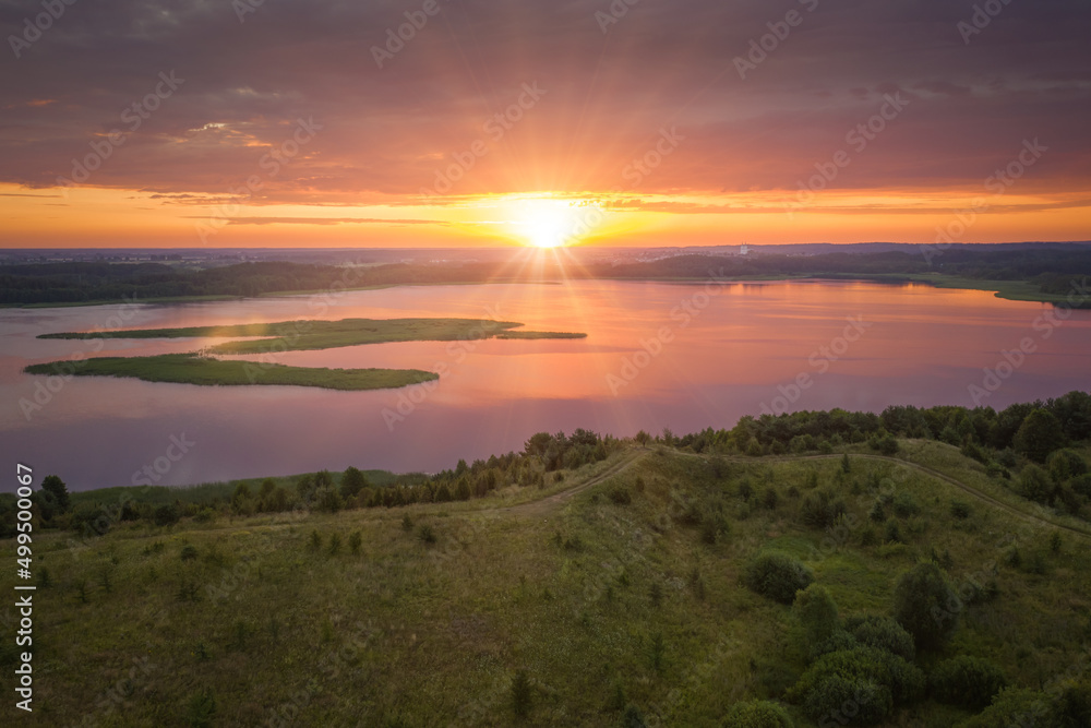 Obraz premium Amazing lake land from above, beautiful islands covered with trees and meadows in morning sunlight. Aerial, flight over Braslav Lakes National Park during fantastic sunrise. Colorful clouds on horizon