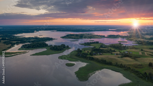 Amazing lake land from above  beautiful islands covered with trees and meadows in morning sunlight. Aerial  flight over Braslav Lakes National Park during fantastic sunrise. Colorful clouds on horizon