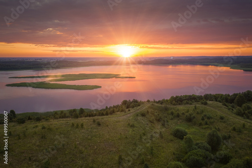 Amazing lake land from above, beautiful islands covered with trees and meadows in morning sunlight. Aerial, flight over Braslav Lakes National Park during fantastic sunrise. Colorful clouds on horizon