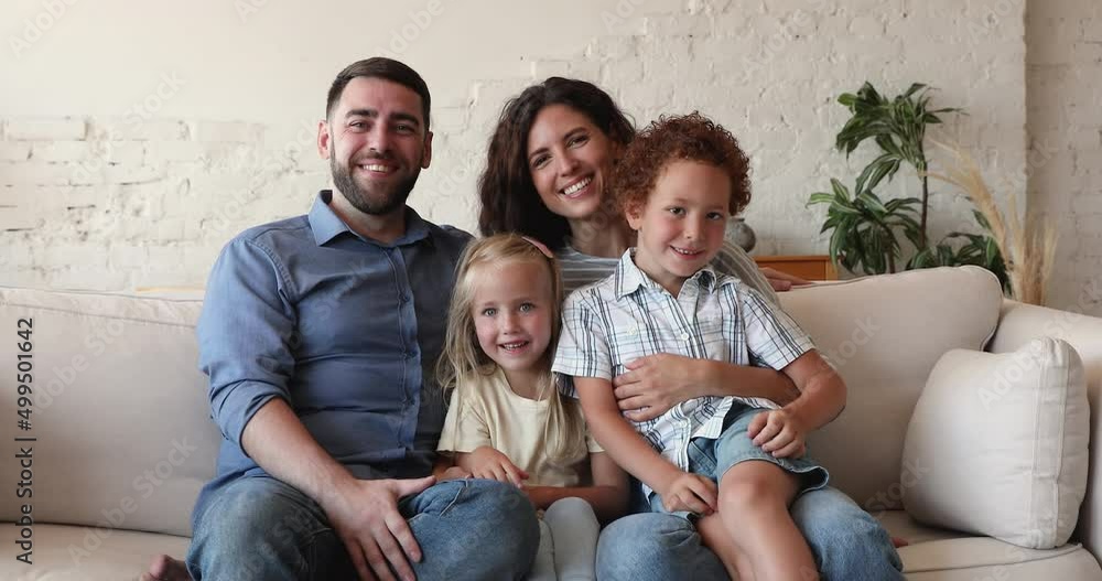 Healthy family portrait smiling couple mother father sit on sofa embrace kids older brother younger sister. Bonding parents with two children siblings daughter son look at camera laugh tickle have fun Healthy family portrait smiling couple mother father sit on sofa embrace kids older brother younger sister. Bonding parents with two children siblings daughter son look at camera laugh tickle have fun