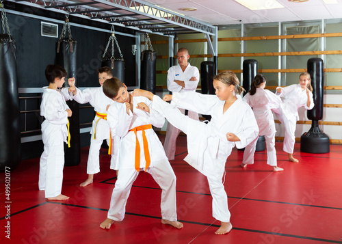 Kids in kimonos exercising techniques in pair during taekwondo class at gym
