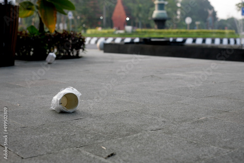 Carelessly thrown away paper cup with plastic on a street in a city