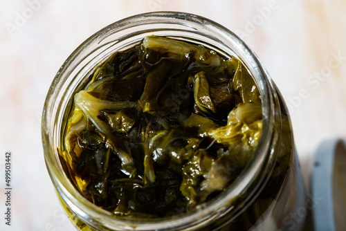Pickled swiss chard with spices in glass jar on a wooden table. High quality photo