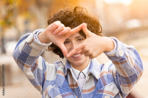 Young brunette woman with curly hair making the Framing sign with her hands photo