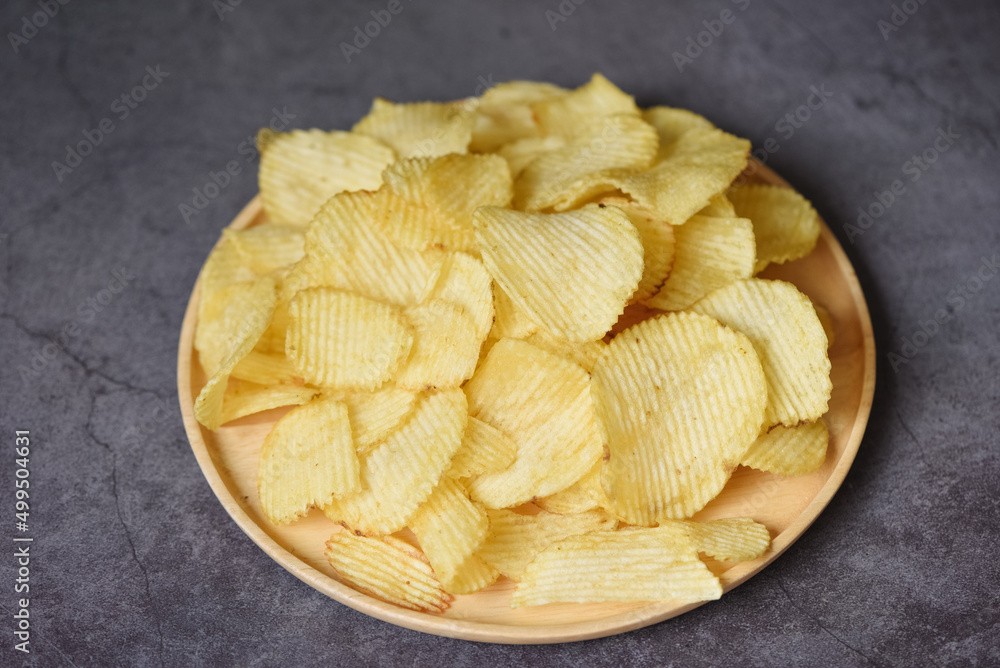 Crispy potato chips on the kitchen table black background, Potato chips snack on plate - top view Crispy potato chips on the kitchen table black background, Potato chips snack on plate - top view