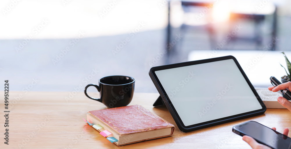 A businesswoman using digital tablet and holding smartphone over her office desk. A businesswoman using digital tablet and holding smartphone over her office desk.