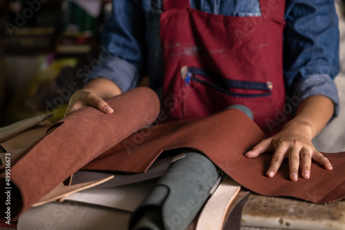 Fotografi Tanner woman selective leather goods on workshop, Selected pieces of beautifully colored or tanned leather on leather craftman work desk, Working process of leather craftsman