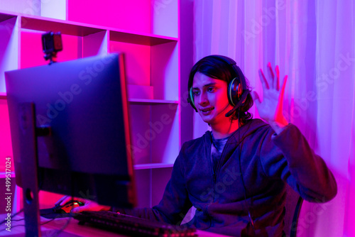 Men play E-Sport games or streamers, Waving to the audience, Male enjoying playing online games, Entertainment  or technology game trends, Professional live performance, Red and blue background. © Puwasit Inyavileart