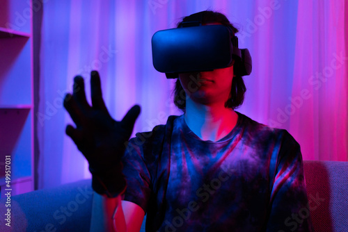 Man wearing virtual reality glasses is playing a 3D game with excitement  Bluetooth Remote Controller  VR  Future games  Gadgets  Technology  Red and blue background  VR game concept.