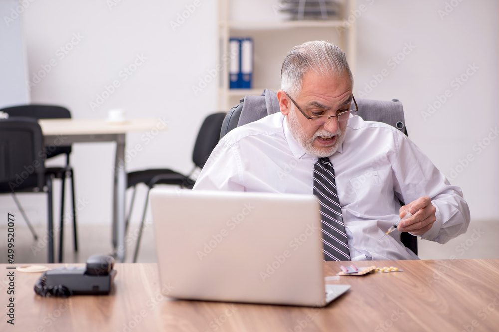 Aged male employee suffering at workplace Aged male employee suffering at workplace