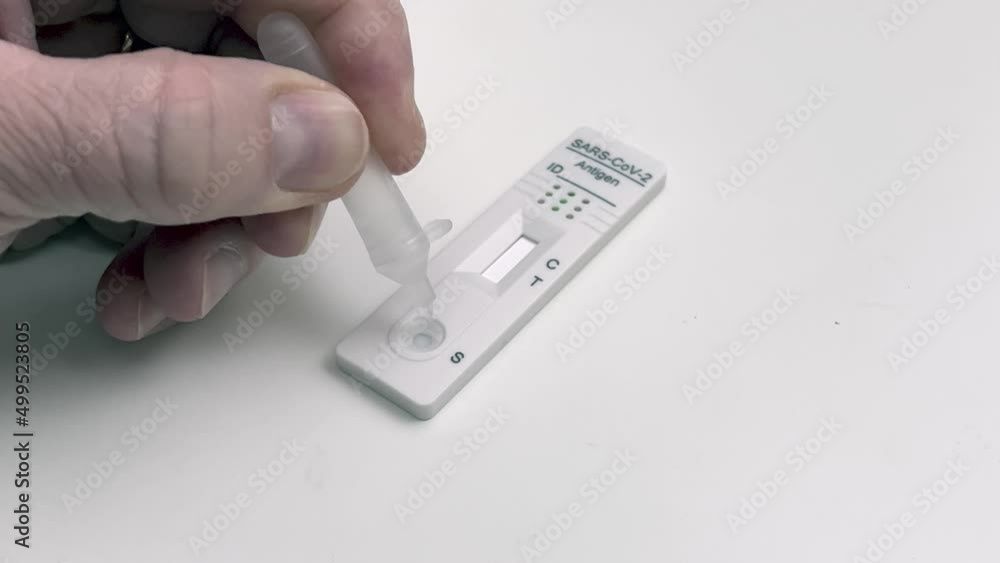 Performing COVID-19 antigen flow test. Pipette drops the sample onto the test pad. Wide framing. Performing COVID-19 antigen flow test. Pipette drops the sample onto the test pad. Wide framing.