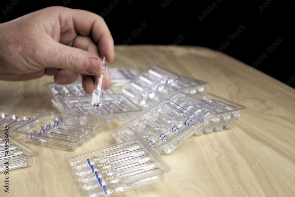 a man puts ampoules with medicines on the table, and in his hand he has an ampoule