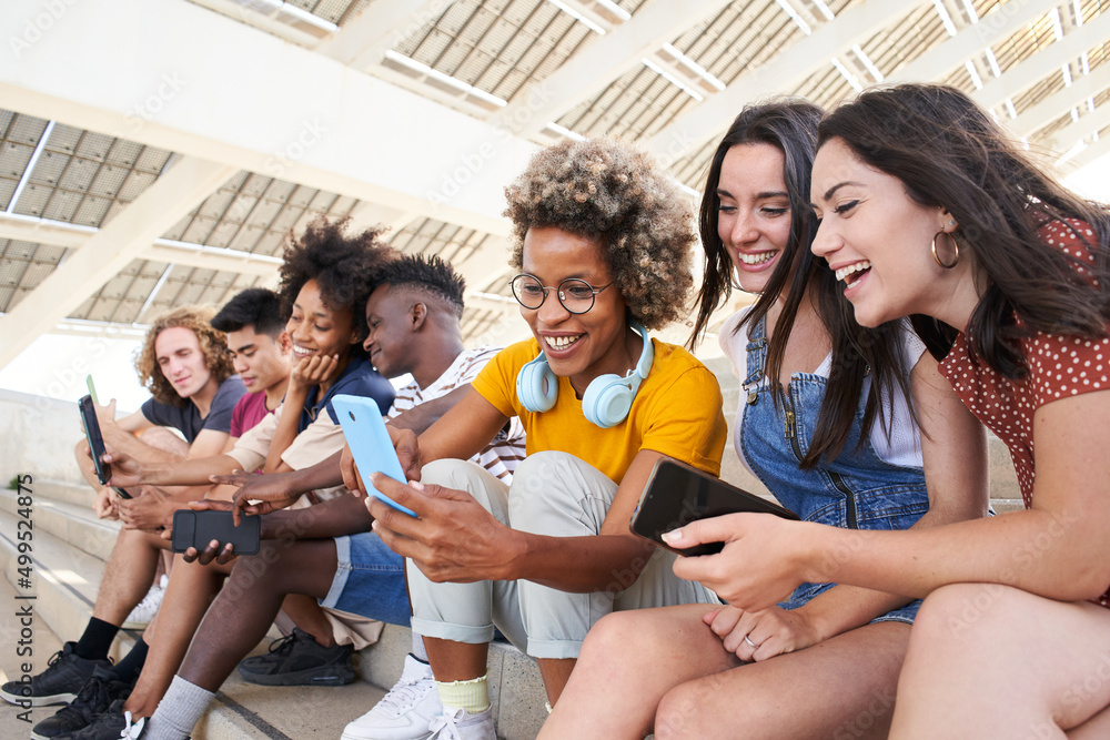 Group of young mixed race people with mobile phones. Excited students using their technological devices. Concept of young enterprising, friendly, selfie, app, hipster, millennial. - obrazy, fototapety, plakaty 