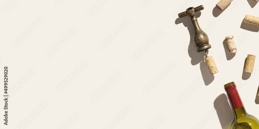 Background with wine corks, old corkscrew, wine bottle on beige pastel color with shadow at sunlight, copy space. Wide banner with natural wooden bottle cap, metal vintage opener, copyspace Background with wine corks, old corkscrew, wine bottle on beige pastel color with shadow at sunlight, copy space. Wide banner with natural wooden bottle cap, metal vintage opener, copyspace