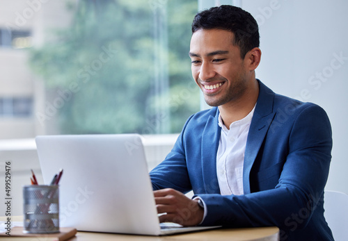 This proposal is looking good. Shot of a young businessman working on his laptop.