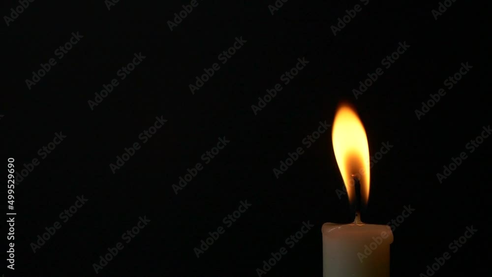 Slow motion closeup burning single candle flame isolated on black background Slow motion closeup burning single candle flame isolated on black background