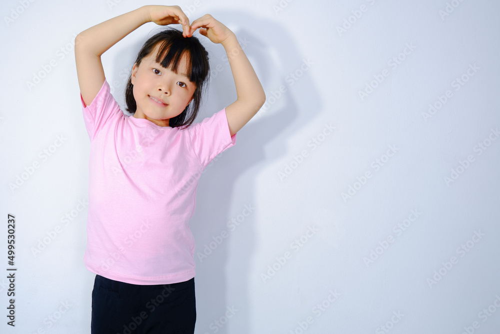 Portrait of a beautiful Asian woman with a heart-shaped hand gesture on a smiling face on a plaster background. Asian girl wearing casual clothes lifestyle cute girl Valentine's Day concept. Portrait of a beautiful Asian woman with a heart-shaped hand gesture on a smiling face on a plaster background. Asian girl wearing casual clothes lifestyle cute girl Valentine's Day concept.