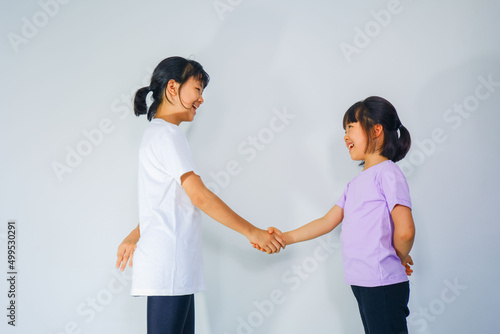 Two beautiful Asian women shake hands with smiling faces on plaster.