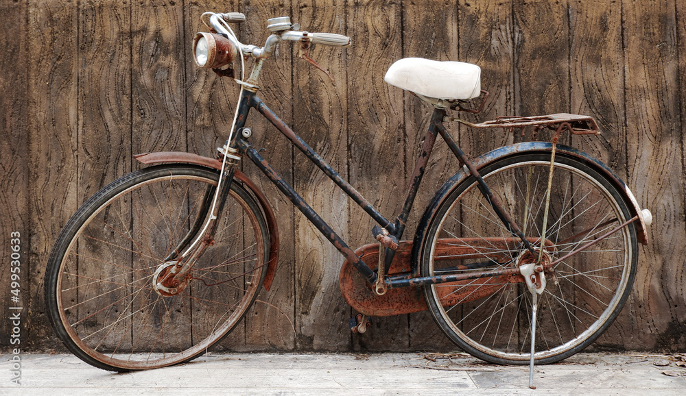 Image of an old bicycle in an outdoor park on a rough plaster background.