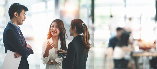Business people talking and discussing together while standing at co-workspace.