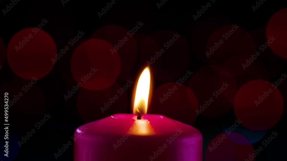 decorative red candle burns against the background of festive blue flashing lights decorative red candle burns against the background of festive blue flashing lights