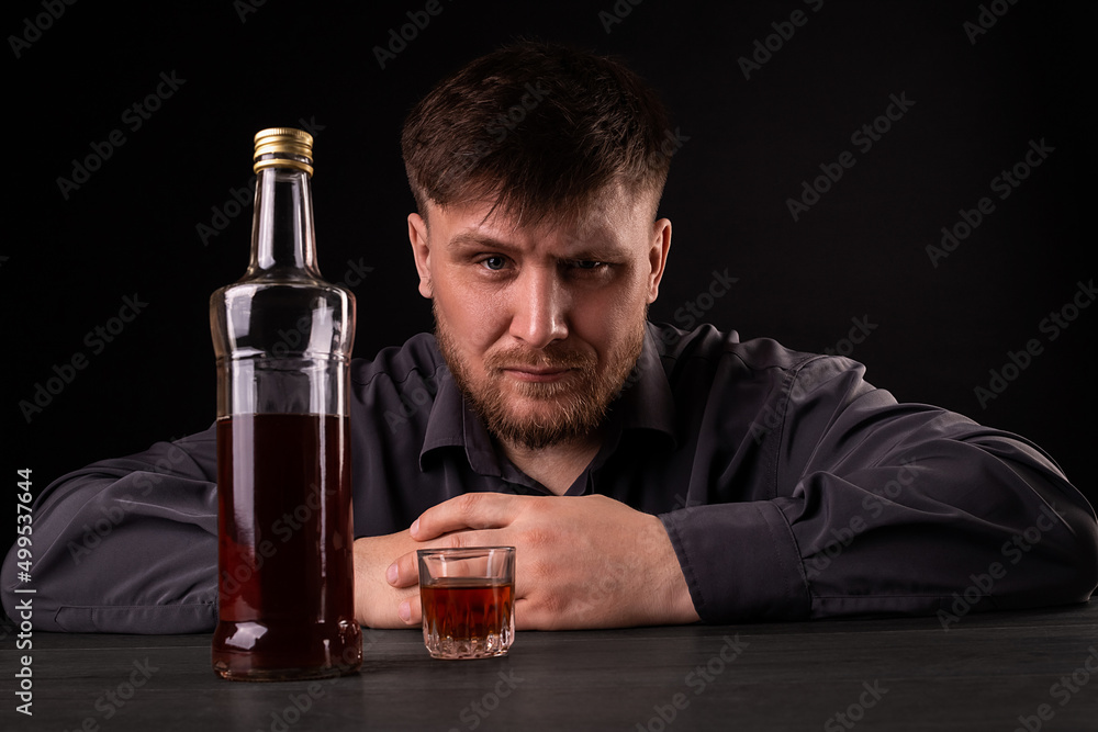 A man with a beard drinks alcohol. A man with a beard drinks alcohol.
