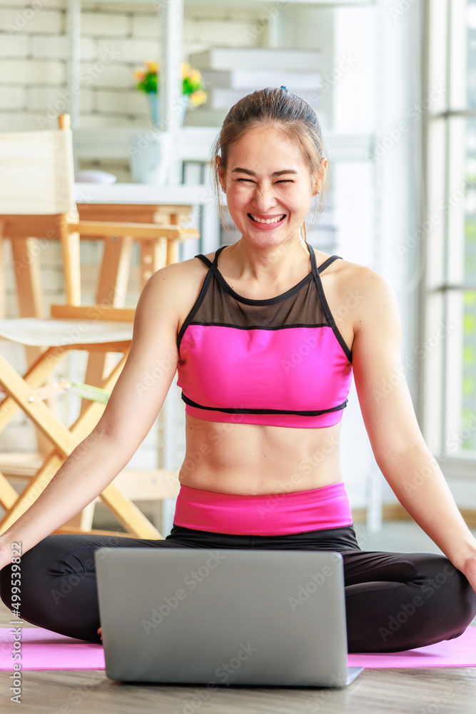 Asian young beautiful sexy slim strong female sporty model in crop top sportswear sitting smiling stretching crossed legs and arms cool down on yoga pilates mat in apartment living room after workout Asian young beautiful sexy slim strong female sporty model in crop top sportswear sitting smiling stretching crossed legs and arms cool down on yoga pilates mat in apartment living room after workout