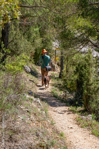 Hombre con sombrero y perro paseando en el bosque