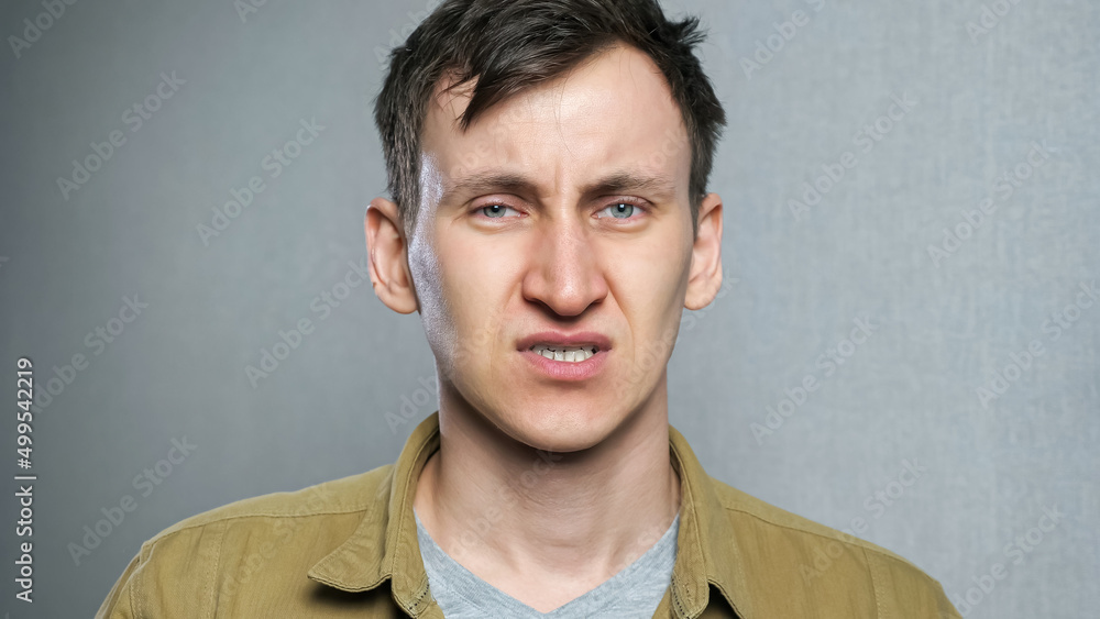Depressed young man feels stressed and desperate. Portrait of anxious handsome on gray background. Depressed young man feels stressed and desperate. Portrait of anxious handsome on gray background.