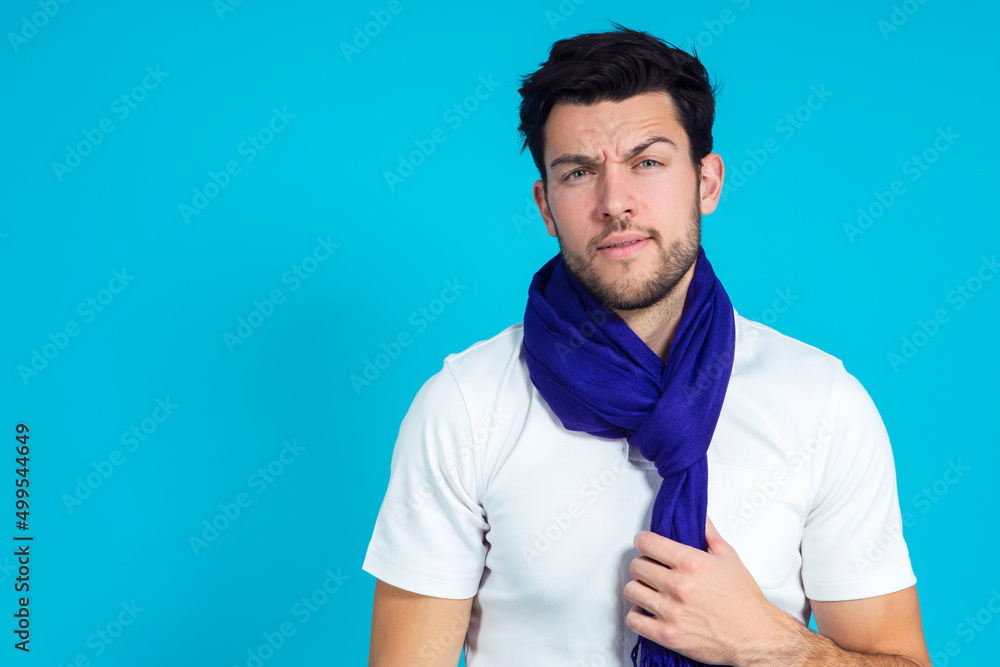 Lifestyle Ideas. Caucasian Handsome Man Posing in White Shirt And Blue Scarf While Smiling And Looking Straight to Camera Over Blue Background. Lifestyle Ideas. Caucasian Handsome Man Posing in White Shirt And Blue Scarf While Smiling And Looking Straight to Camera Over Blue Background.