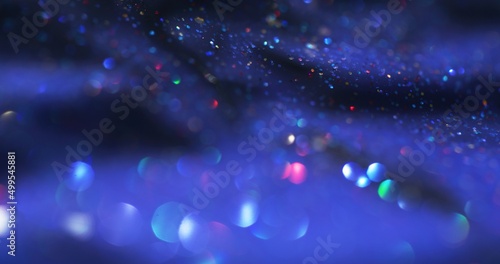 Bokeh light. Glitter bubbles. Lens flare overlay. Defocused neon colorful shimmering circles on dark blue grain texture abstract background.