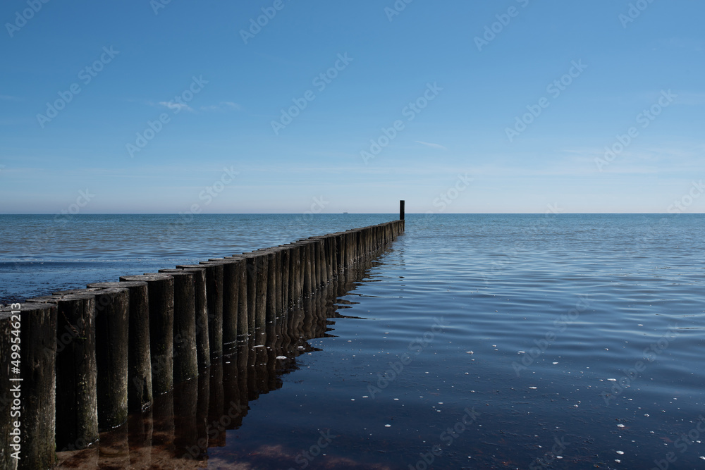 maritime background, wooden breakwater in calm baltic sea against blue sky - obrazy, fototapety, plakaty 