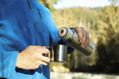 Man pour drink from thermos to cup outdoor