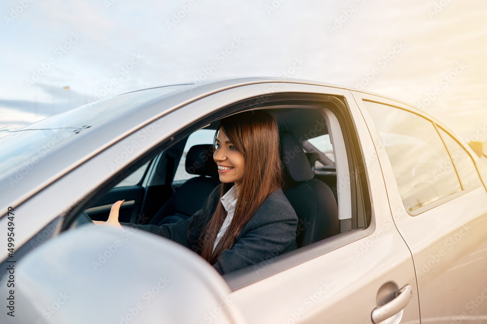 Beautiful young happy smiling woman driving her new car.