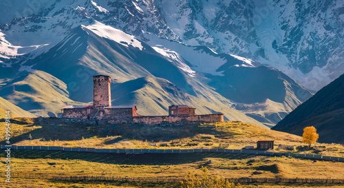 Gorgeous autumn view of ancient Lamaria church in Ushguli village. Splendid morning view of snowy Shkhara hills in Upper Svaneti, Caucasus mountains, Georgia, Europe. Traveling concept background. photo