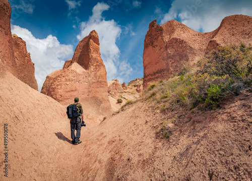 Photographer walks among huge sandstone peaks in Cappadocia. Majestic morning view of of Red Rose valley, Cavusin village location, Turkey, Asia. Traveling concept background..