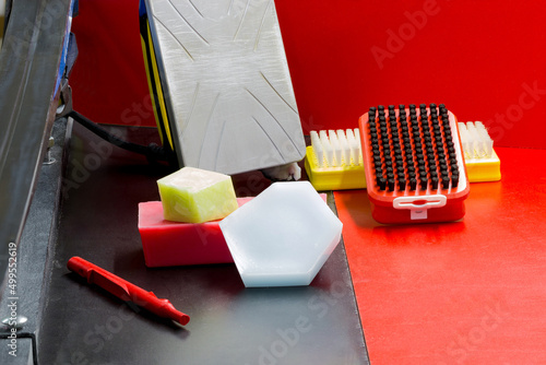 Ski and snowboard preparation kit: iron, brushes, scraper, ski grease - paraffin, skis on black and red backgrounds