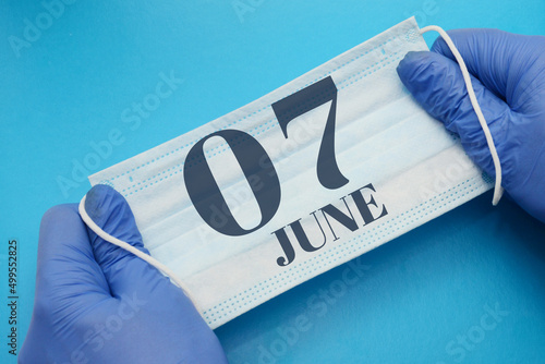 7 june day of month. Doctor holding an antivirus mask in blue medical gloves on blue background. Protection from disease