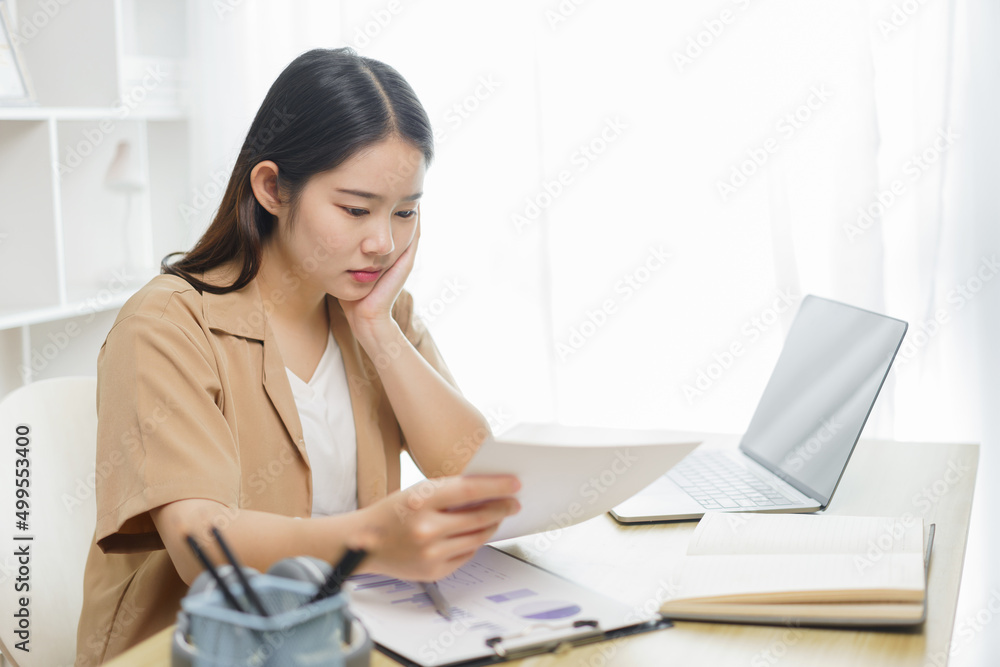 Online lifestyle concept A female home worker seriously concentrating on reading some data from the paper . Online lifestyle concept A female home worker seriously concentrating on reading some data from the paper .