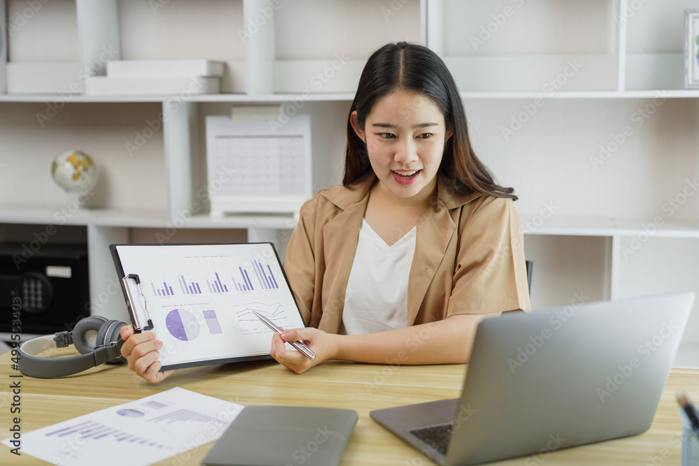 Online lifestyle concept A female home worker explaining her diagrams on the paper to her boss on the online meeting. Online lifestyle concept A female home worker explaining her diagrams on the paper to her boss on the online meeting.