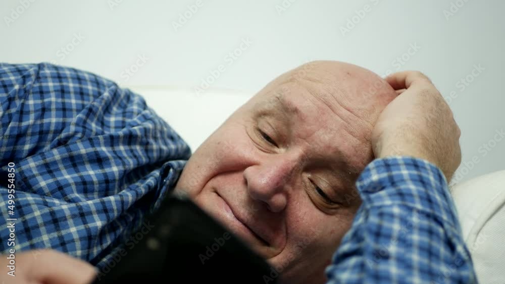 Relaxed Person Sitting on a Couch, Smiling Happy Sending and Reading Messages Using a Mobile Phone. Relaxed Person Sitting on a Couch, Smiling Happy Sending and Reading Messages Using a Mobile Phone.