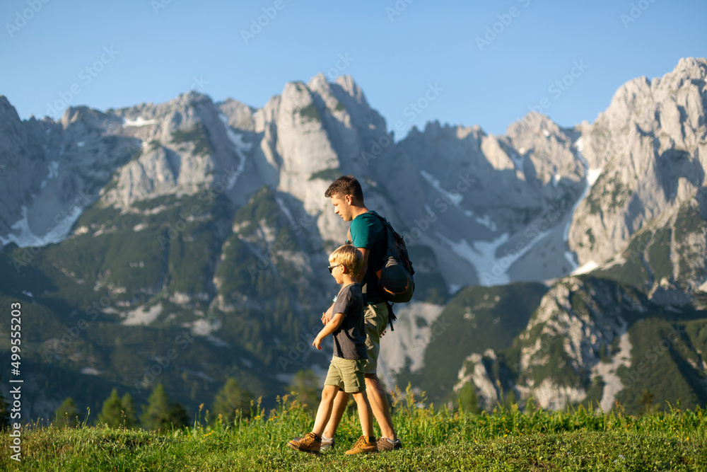 Father and his teenage son enjoying the mountain landscape during their hike in the Austrian Alps 