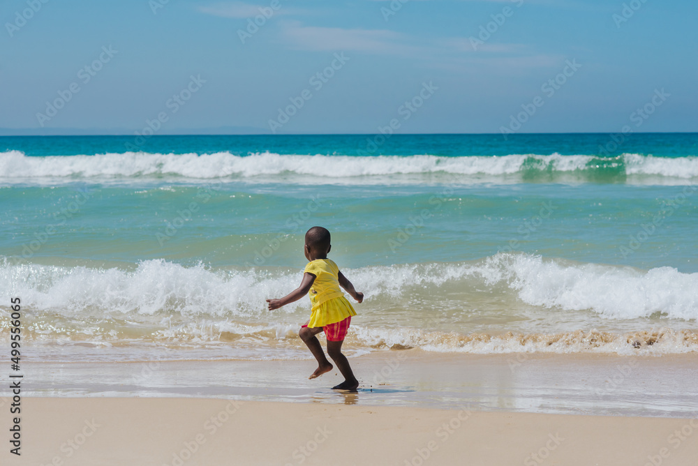 Kleines farbiges Kind hat Spaß am türkisfarbenen Meer in Südafrika am Strand Kleines farbiges Kind hat Spaß am türkisfarbenen Meer in Südafrika am Strand