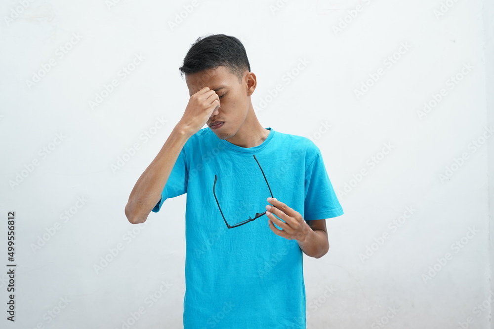 Young asian wearing unhealthy blue tshirt with glasses, rubbing eyes
