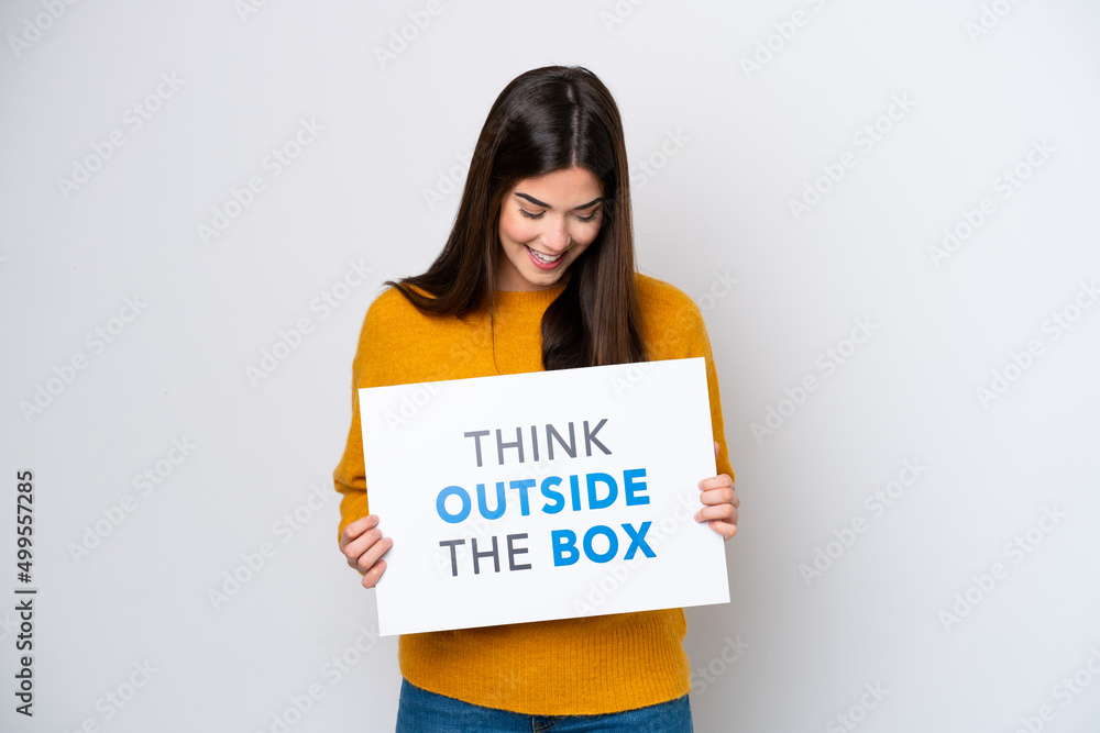 Young Brazilian woman isolated on white background holding a placard with text Think Outside The Box Young Brazilian woman isolated on white background holding a placard with text Think Outside The Box