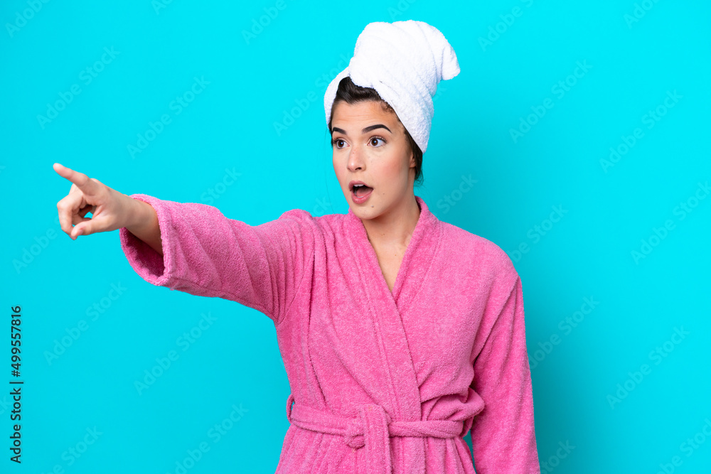Young Brazilian woman with a bathrobe isolated on blue background pointing away Young Brazilian woman with a bathrobe isolated on blue background pointing away